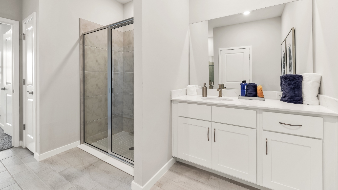Inside the Lantana model bathroom. White cabinets and counter top sink vanity. Tile shower.