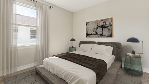 Inside of the Shelby model bedroom three. Creme carpet with off-white walls. Room contains bed with small nightstands on either side. Room also has window.