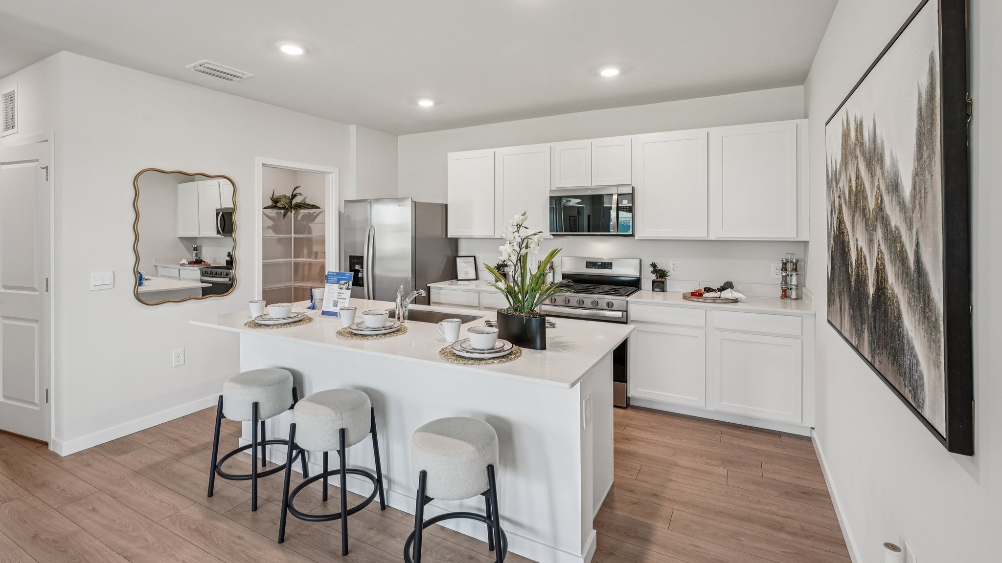Inside the Carrington kitchen. All white cabinets and counter tops with stainless steel appliances. Bar style seating.