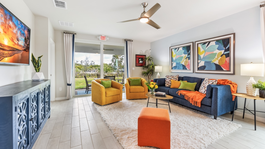 Colorful living room with credenza, couch, two chairs, coffee table, and side table. Sliding glass doors leads out to the covered lanai.