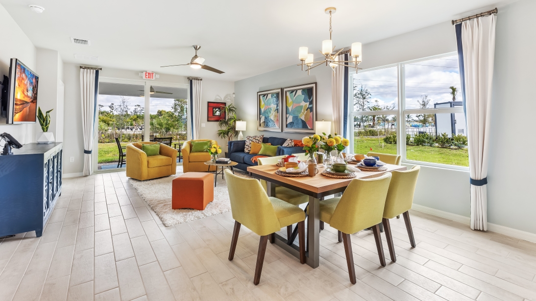 Colorful living room and dining area with a window view outside and sliding glass doors that lead to the covered lanai.
