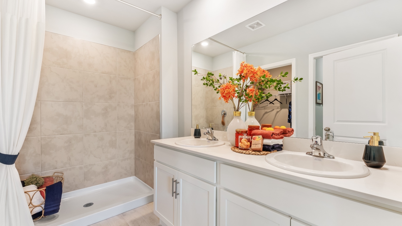 Primary bathroom with a walk in shower and dual-sink vanity.