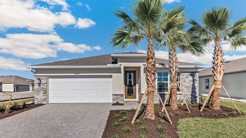 Exterior elevation of white home with gray and tan stone, brown door and gray paver driveway.