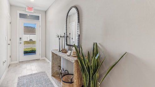 Inside of the Cali model hallway. Tile flooring, off-white walls. Hallway to the front door and den area.