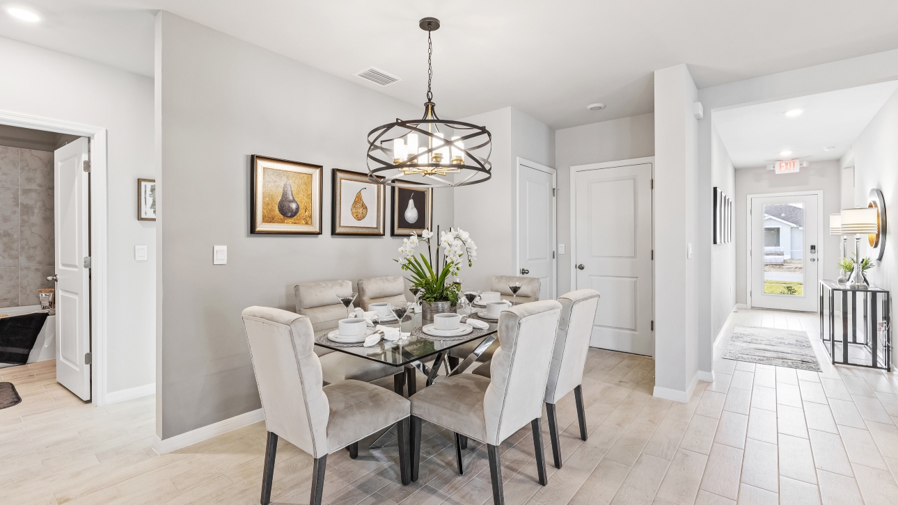Inside the Lakeside Model Dining Area. You can see the front door from here. Floor is tiled and walls are painted grey. All silver/neutral furnishings. The area can fit up to 6 people and there is a bathroom nearby.