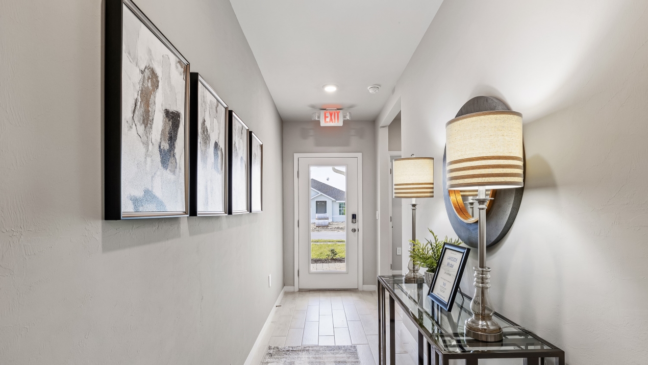 Inside of the Lakeside model hallway. Tile flooring, Grey walls. Hallway to the front door and den area.