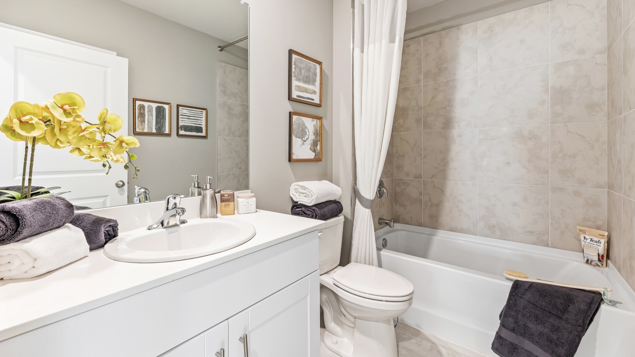 This is the Lakeside's secondary bathroom, The shower has a tub and the porcelain tub and sink have silver fixtures.
