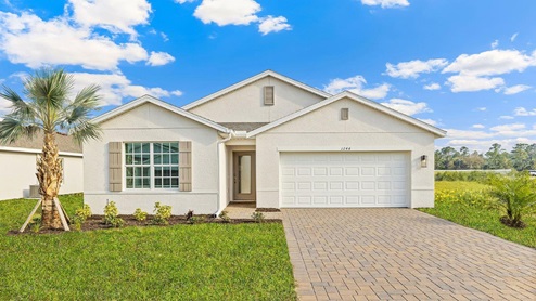 Exterior elevation of white home with white trim, tan doors and shutters, with tan paver driveway.