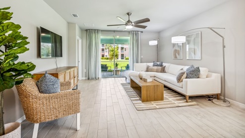 Inside of the Carrington model. Wood tile flooring with off-white walls. Room contains a couch, an armchair, coffee table, and small side table.