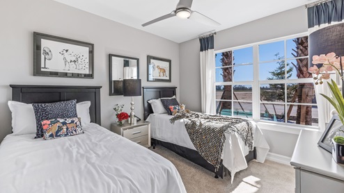 Inside of the Cali model bedroom three. Crème carpet with white walls. Room contains bed with nightstand on either side as well as a dresser on the opposing wall. Room also has window.