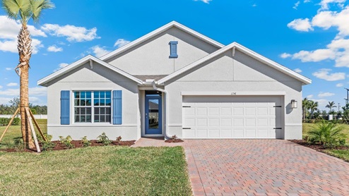 Outside of the Cali D model. Grey home with a two car garage, one window with shutters, and front door. Mixed pavers driveway.