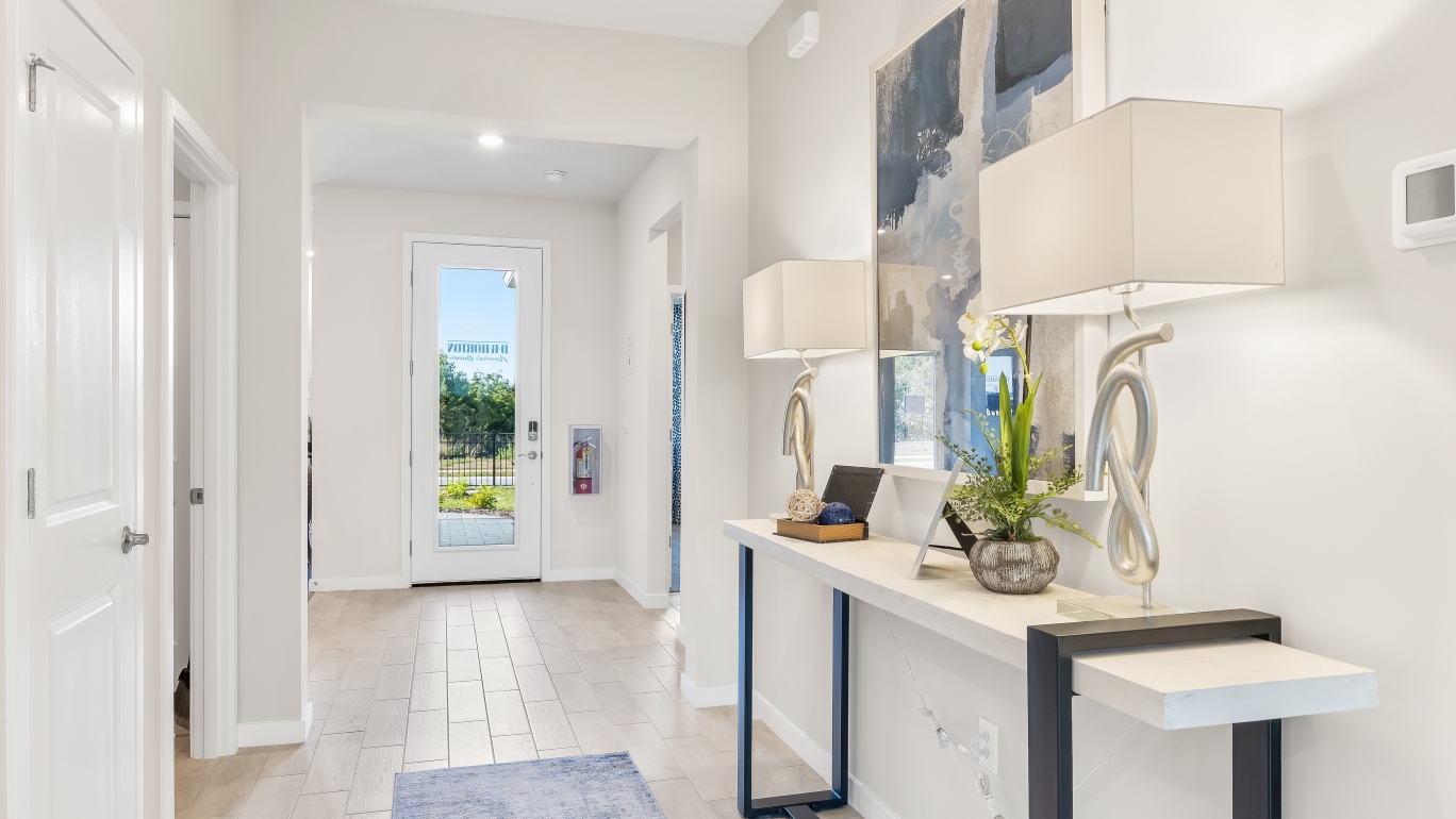 Inside the front door of the Lantana model. Revwood floors with white walls, an entry table, and mirror.