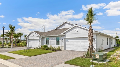 Exterior elevation of white home with two garages, white trim and light tan paver driveways.