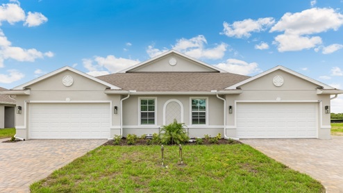Exterior elevation of white home with two garages, white trim and light tan paver driveways.