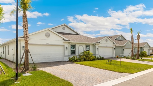 Exterior elevation of white home with two garages, white trim and light tan paver driveways.