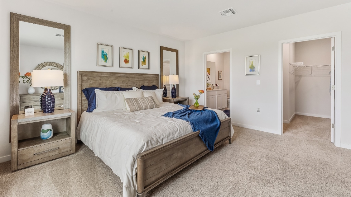 Inside of the Carrington model primary bedroom. View of the walk in closet and the bathroom
