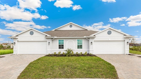 Exterior elevation of white home with two garages, white trim and light tan paver driveways.