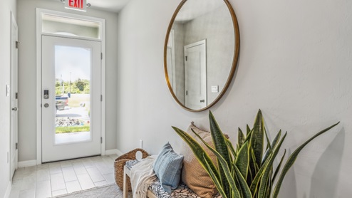 Inside of the Cali model hallway. Wood tile flooring, off-white walls. Hallway to the front door and den area.