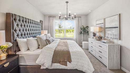Inside of the Cali model bedroom. This photo of the bedroom shows that there is a dresser opposing the bed as well as a window.
