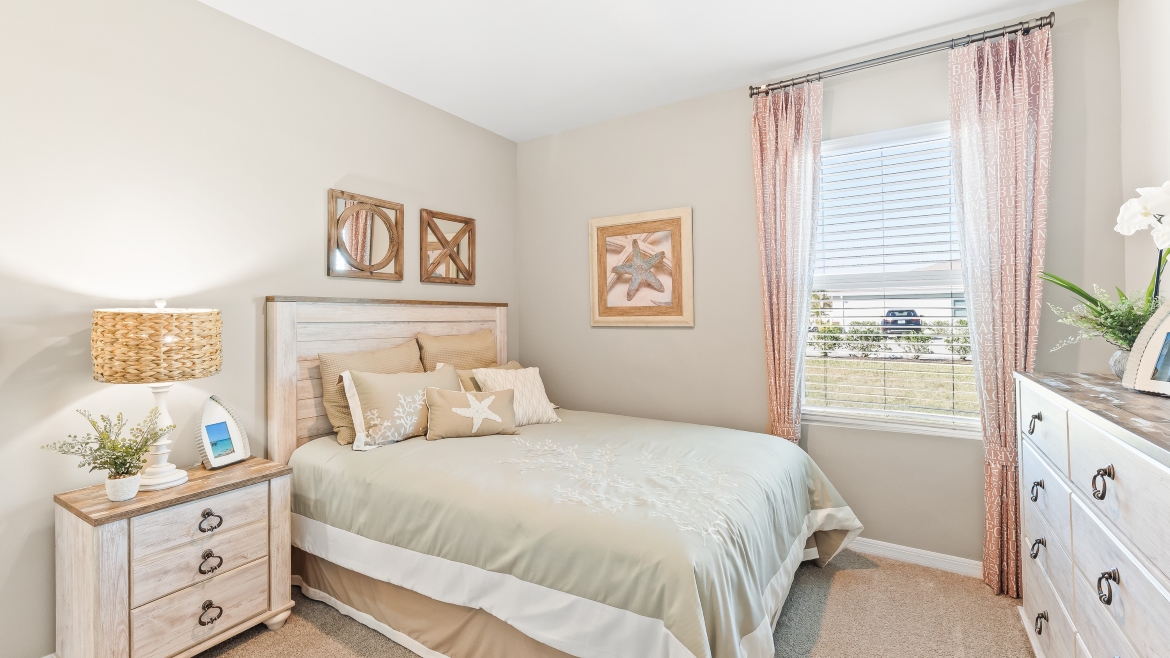 Inside of the Cali model bedroom 2. This room has a bed with nightstands on either side, and a dresser across from the bed.