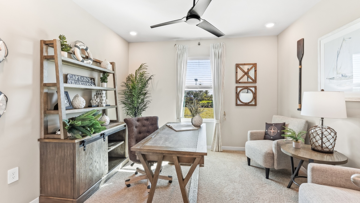 Inside the Cali model bonus room. This room has a desk with a desk chair, storage shelves, two chairs and a coffee table.