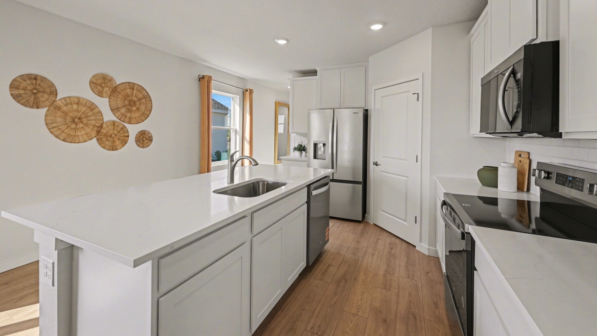 Inside of the Harper model in Central, FL. Kitchen with stainless steel appliances and island with bar seating.