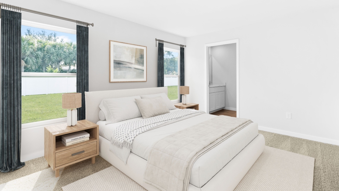 Inside of the Dundee model bedroom one. Creme carpet with white walls. Room contains a large bed with nightstands on either side.