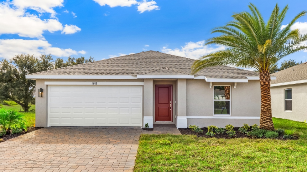 Outside of the Freeport II model. Beige home with a front door, two car garage, window with shutters, and a light paver driveway.