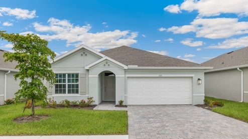 Outside of the Aria C model. Off-white home with two car garage, one large window with shutters, and front door. Mixed pavers driveway.