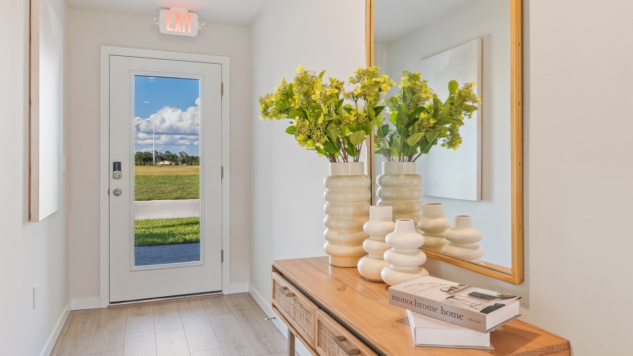 Front door of the Freeport II model. Front entry table with a mirror and flowers. Revwood floors with white walls.