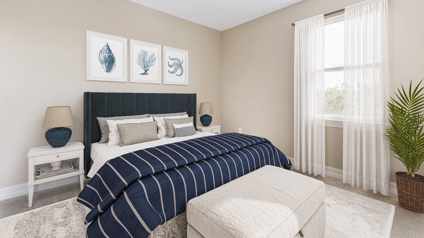 Inside the Kellen model third Bedroom with view of the large window with curtains. Walls are sand and carpet is gray.  Bedding is dark grey, white and navy blue. There are two white side tables on either side of the bed with lamps on each and a bench at the foot of the bed.