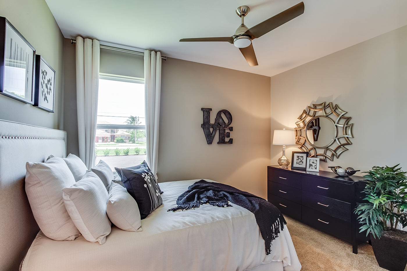 Inside of the Destin model bedroom one. Crème carpet and off-white walls. Room contains a bed and dresser as well as a window.