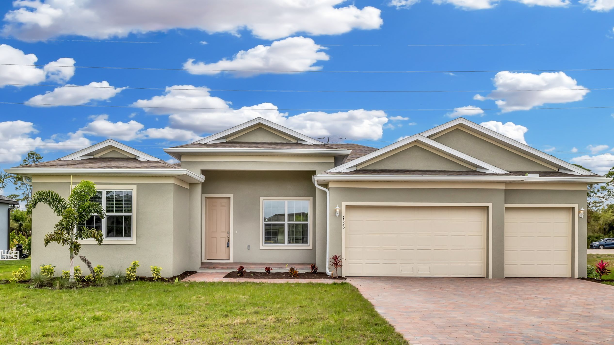 Outside of the Sage A model. Grey home with three car garage, two windows, and door up front. Grey paver driveway.