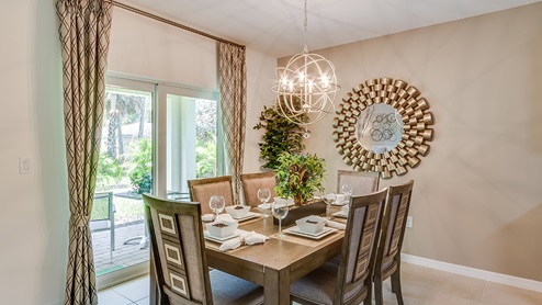 Inside of the Cali model dining room. The dining room contains a six-person dining table and chairs. The living room can be seen in the background as well as the sliding glass door that leads to the back patio.