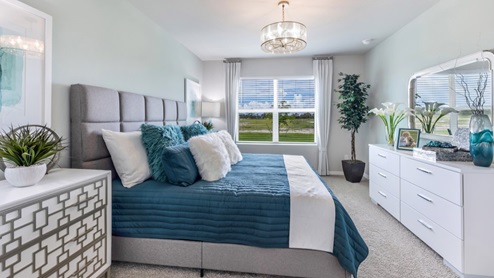 Inside of the Cali model bedroom. This photo of the bedroom shows that there is a dresser opposing the bed as well as a window.