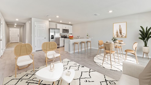 Inside of the Freeport kitchen. Wood tile floors off-white walls. Kitchen has white countertops with bar-style seating on side closest to dining room. Stainless steel refrigerator, microwave, and stove. Kitchen connects to dining room, living room, and hallway that leads to front door.