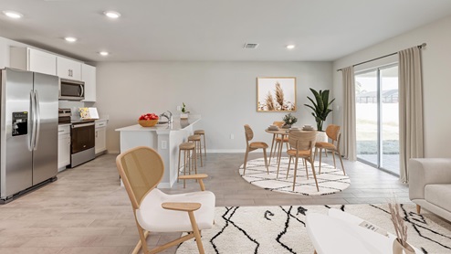 Inside of the Freeport kitchen. Wood tile floors off-white walls. Kitchen has white countertops with bar-style seating on side closest to dining room. Stainless steel refrigerator, microwave, and stove. Kitchen connects to dining room as well as living room.