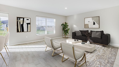 Inside of the Boardwalk living room area. Grey wood tile and off-white walls. Living area connects to dining area and kitchen as well as door to back patio. Living area contains two armchairs, small couch, coffee table, and small plant in corner. Window brings light into the living area.