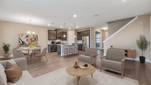 Inside the Coral home, you can see the kitchen, dining room, living room and staircase from here. Cabinets are dark wood and floor is wood tiling.