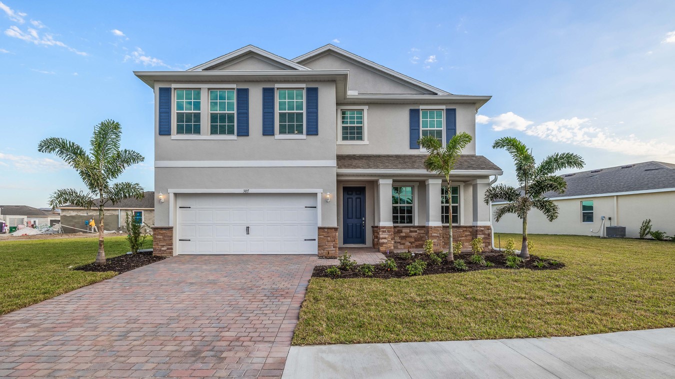 Outside of the Coral H elevation. A Beige two-story home with a two car garage and paved driveway.