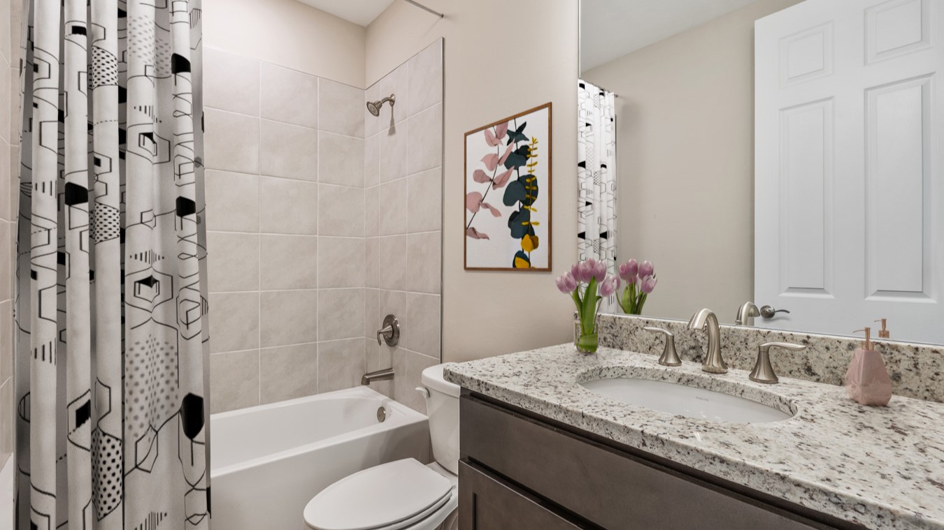 Inside the Coral secondary bathroom with single sink, dark wood cabinets and a shower/tub combo next to the toilet.