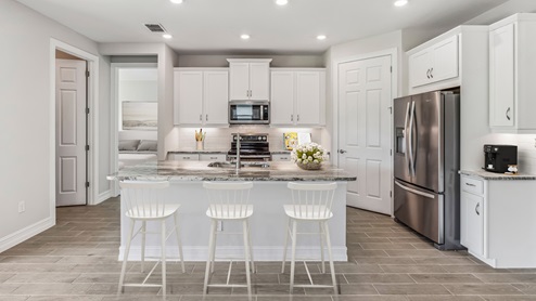 Inside the Clifton kitchen, there is an island with a bar top, brand new silver appliances and white designer cabinets.