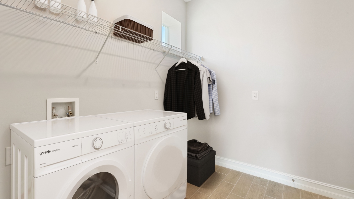 Inside of the Shelby model laundry room. Washer and Dryer space with racks to store cleaning supplies