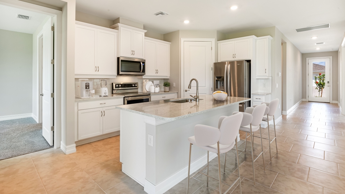Another angle of the Inside of the Clifton A.  Kitchen has stainless steel appliances. There is bar seating in the kitchen. Can see the entry hall to the front door.