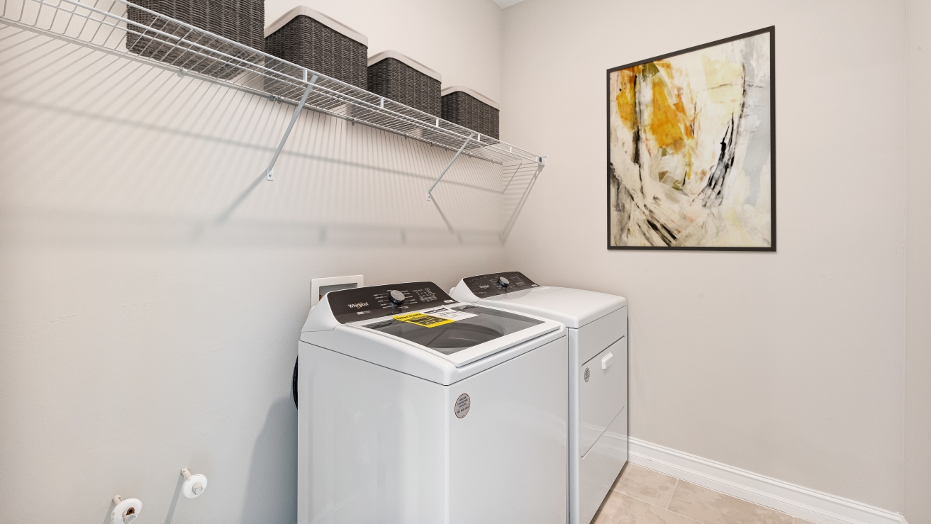 Inside of the laundry room with washer and dryer space. Shelving for laundry items