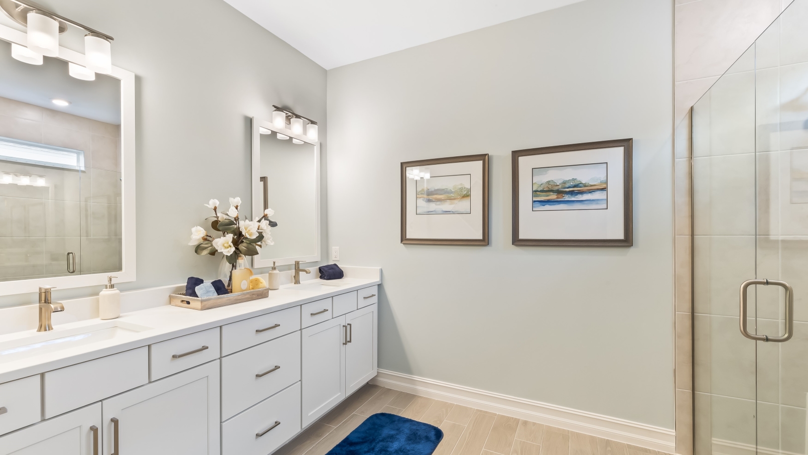 Inside of the primary bathroom. Dual sink vanity with a shower