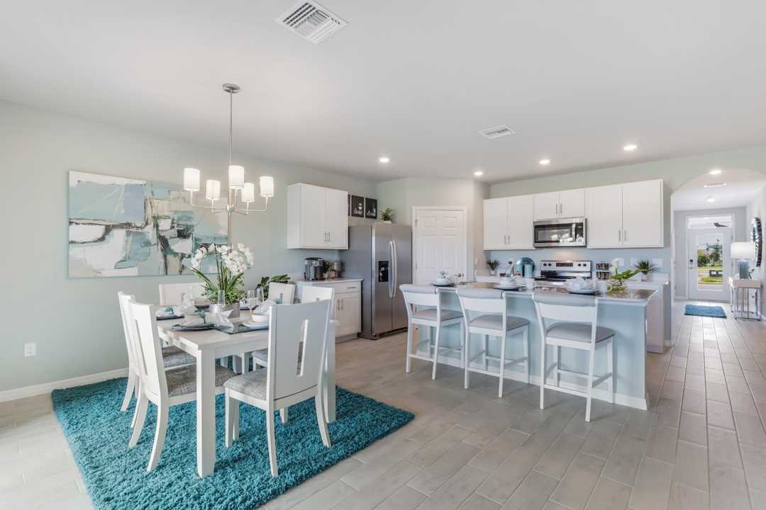 Inside of the Cali model dining area and kitchen. This photo demonstrates how the kitchen and dining area can be seen at all times thanks to the kitchen's open concept. In the background the hallway leading to the front door and other bedrooms can be seen.