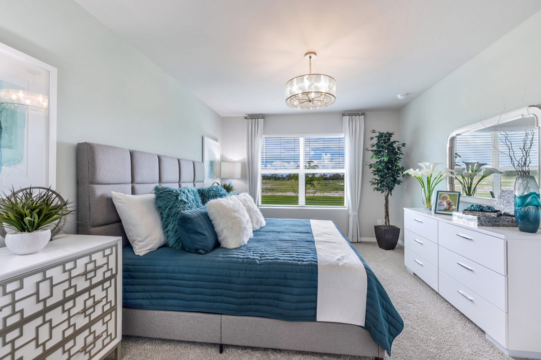 Inside of the Cali model bedroom. This photo of the bedroom shows that there is a dresser opposing the bed as well as a window.
