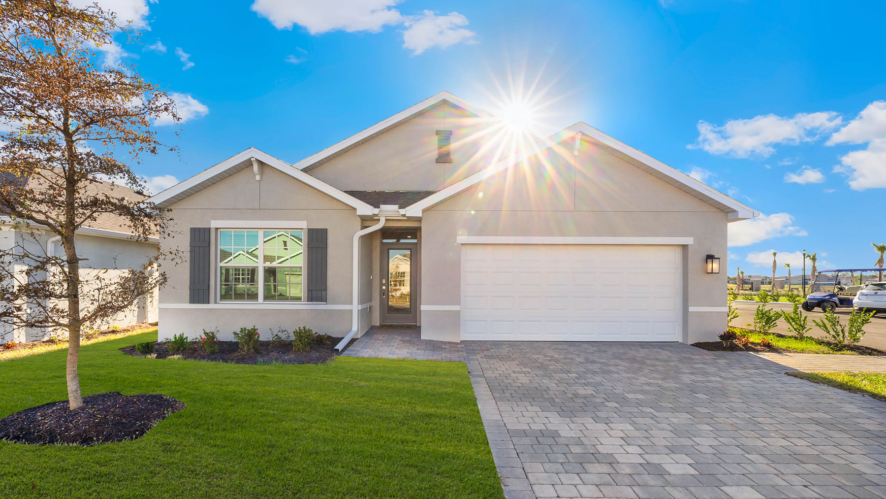 Outside of the Cali model D home. Beige home, two car garage, window with shutters, and front door. Mixed paver driveway.