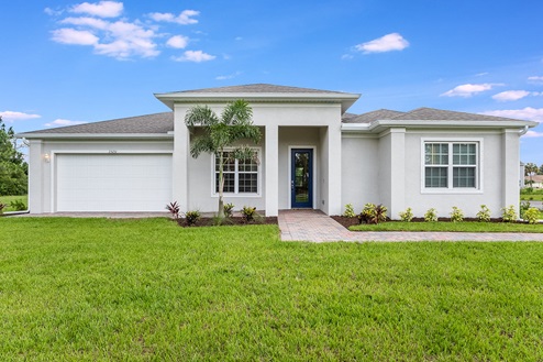 Outside of the Kellen model. Off-white home with two car garage, two windows, and front door. Mixed pavers driveway.
